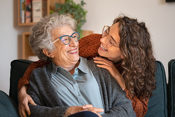 Grandmother and granddaughter laughing and embracing at home