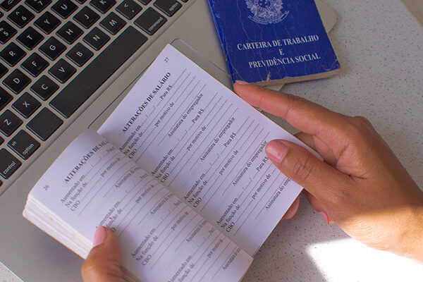 Brazil Work Card. Translation – Federative Republic of Brazil, Ministry of Labor. Brazilian work card in front of a laptop, illustrating the relationship between legal documentation and the job market