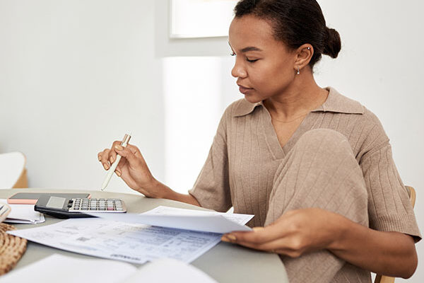 Young Black woman doing taxes at home and using calculator